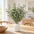 Konstgjord eukalyptus i vit vas på matbord